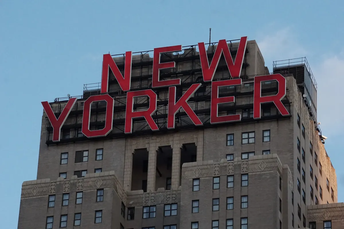 Close-up view of the iconic New Yorker Hotel sign against a clear blue sky in NYC.